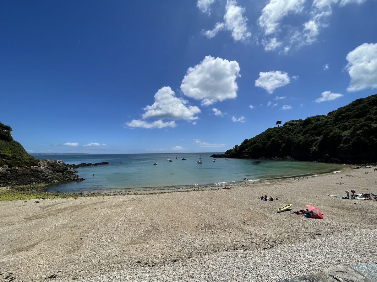 A sheltered Guernsey beach with small boats moored in the bay